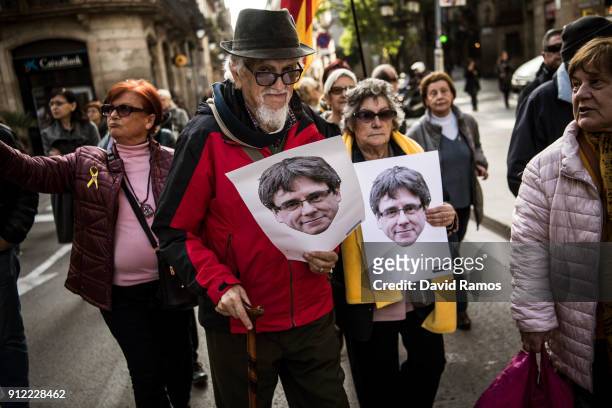 Demonstrators hold cut-out masks of the former Catalan President, Carles Puigdemont as they take part in a protest on January 30, 2018 in Barcelona,...