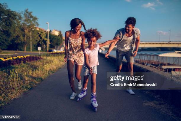 föräldrar hjälpa deras dotter medan rullskridskoåkning vid solnedgången - inline skate bildbanksfoton och bilder