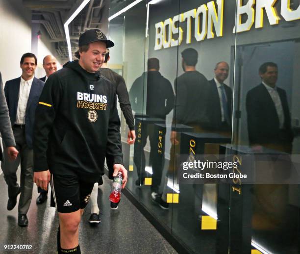 Boston Bruins defenseman Charlie McAvoy smiles after passing some teammates in the hallway while walking into the room for a press conference with...