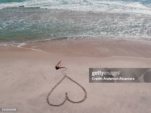deitada na areia da praia segurando coração riscado. praia da barra de gramame, joão pessoa, paraíba, brasil - areia stock-fotos und bilder
