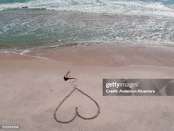 deitada na areia da praia segurando coração riscado. praia da barra de gramame, joão pessoa, paraíba, brasil - areia 個照片及圖片檔