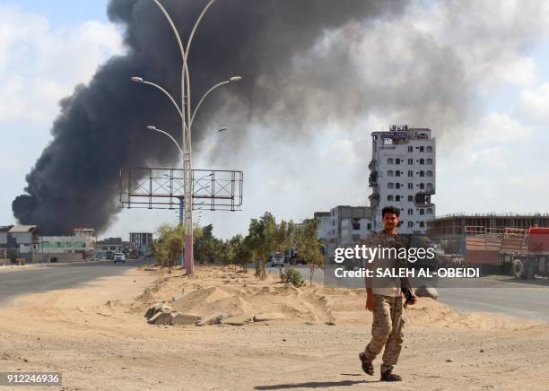 Fighters from the separatist Southern Transitional Council walks with smoke billowing in the background in the government's de facto capital Aden, as...