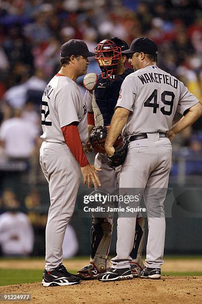 Pitching coach John Farrell, catcher Victor Martinez and pitcher Tim Wakefield of the Boston Red Sox confer on the mound during a break in game...