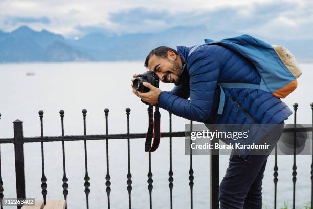 young man photographer shooting on location with backpack - spiegelreflexkamera stock-fotos und bilder