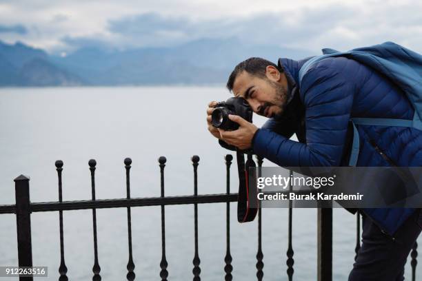young man photographer shooting on location with backpack - spiegelreflexcamera stockfoto's en -beelden