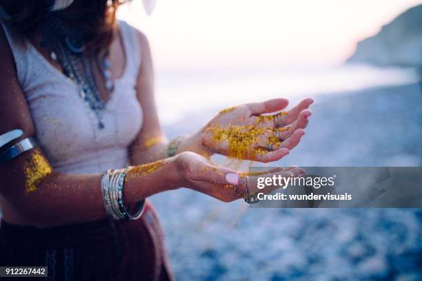 boho-frau am strand mit goldenem glitzer an ihren händen - bracelet festival stock-fotos und bilder
