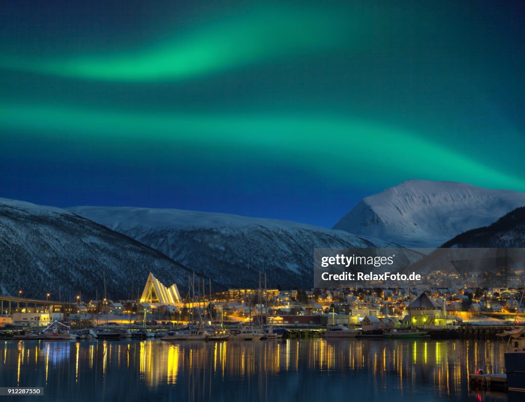 Blick bei Nacht auf beleuchteten Tromso Stadt mit Kathedrale und majestätischen Aurora borealis