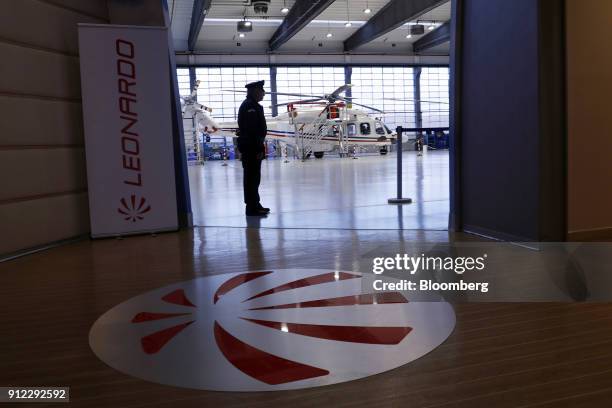 Silhouetted security guard stands in front of a Leonardo SpA AgustaWestland AW189 helicopter during an investor day at a Leonardo plant in Vergiate,...