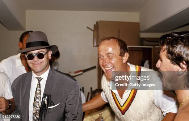 England players Phil Edmonds and Allan Lamb share a joke and their champagne with singer Elton John in the dressing room during celebrations after...