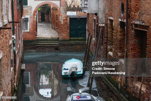Boat is stucked in low tide in a canal on January 30, 2018 in Venice, Italy. An exceptional low tide affected Venice this afternoon creating problems...