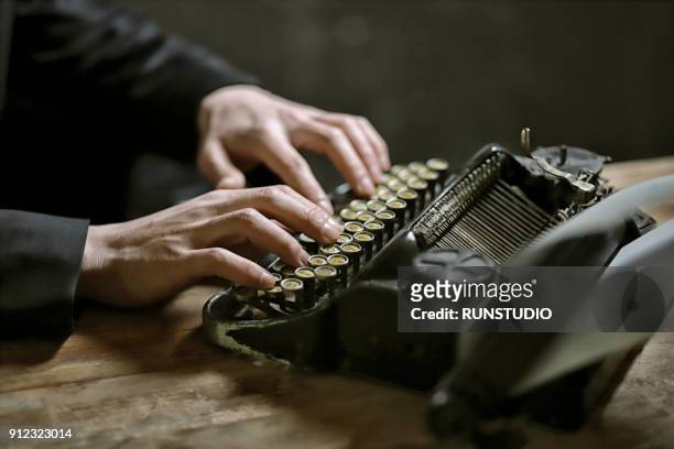 close-up of man using typewrite - typewriter stock-fotos und bilder