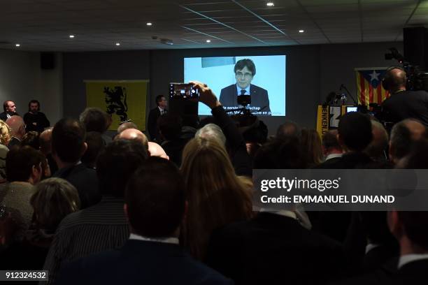 People watch on a screen a live broadcast of a speech by ousted Catalan separatist leader Carles Puigdemont at the New Year reception of the Leuven...