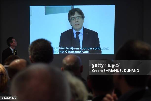 People watch on a screen a live broadcast of a speech by ousted Catalan separatist leader Carles Puigdemont at the New Year reception of the Leuven...