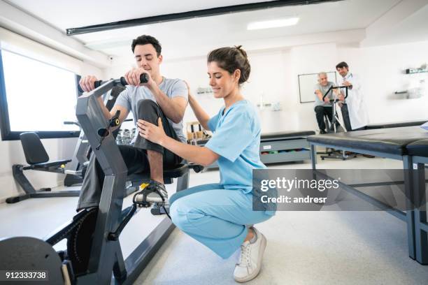 fysiotherapeut corrigeren van de houding van een patiënt op een statische fiets - ergotherapie stockfoto's en -beelden