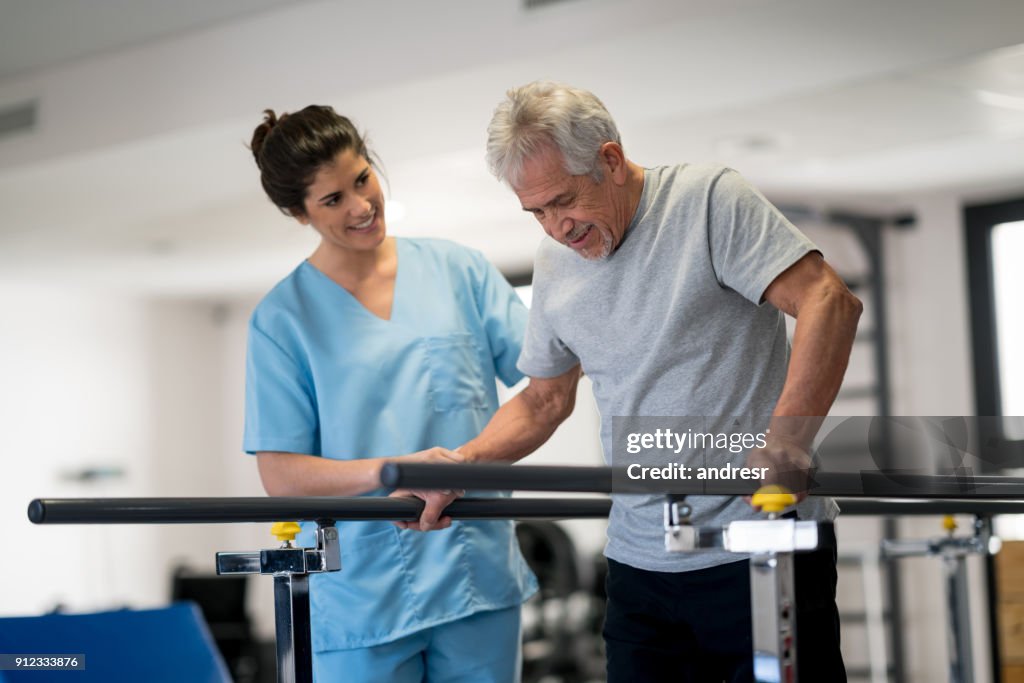 Occupational therapist and senior patient working out using parallel bars to walk