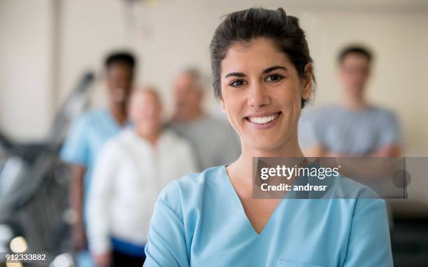 bellissimo fisioterapista in clinica guardando la telecamera sorridente - group of patients foto e immagini stock