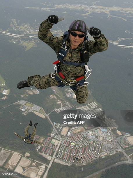 Member of South Korea's special warfare command gives a thumbs up to the camera as he parachutes down from a helicopter during a practice session for...