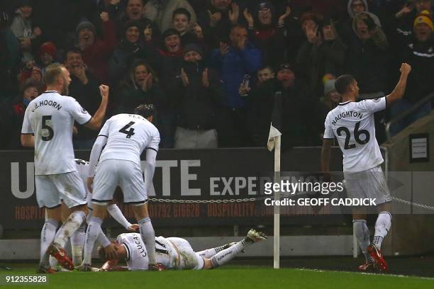 Swansea City's English midfielder Sam Clucas falls to the floor as he celebrates with teammates after scoring his second goal during the English...