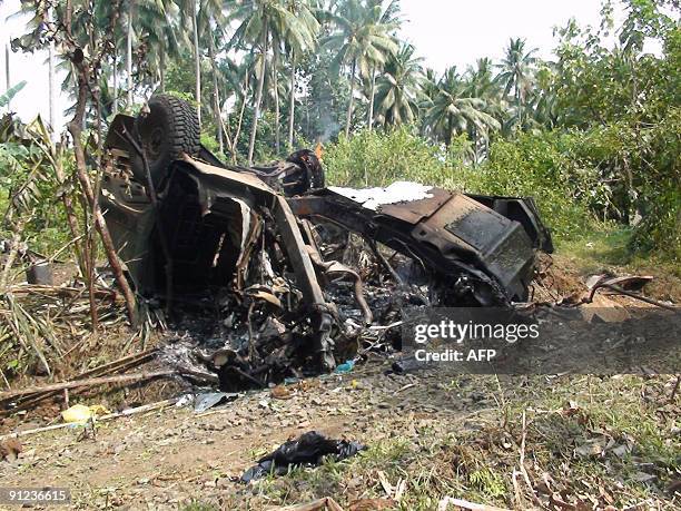 The smoldering remains of a US humvee vehicle lies on the road after a landmine blast in Indanan town, Jolo province in Mindanao island on September...