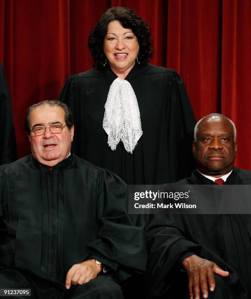 Associate Justice Sonia Sotomayor is flanked by Associate Justice Antonin Scalia and Associate Justice Clarence Thomas while taking a group...