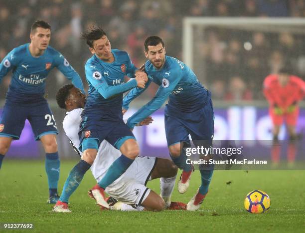 Mesut Ozil and Henrikh Mkhitaryan of Arsenal challenge Leroy Fer of Swansea during the Premier League match between Swansea City and Arsenal at...