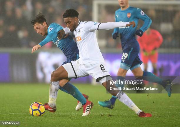 Mesut Ozil of Arsenal challenged by Leroy Fer of Swansea during the Premier League match between Swansea City and Arsenal at Liberty Stadium on...
