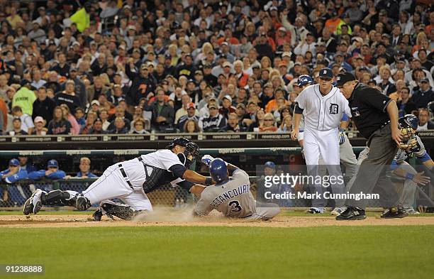 Yuniesky Betancourt of the Kansas City Royals slides into home while Gerald Laird of the Detroit Tigers makes the tag as Eddie Bonine and homeplate...