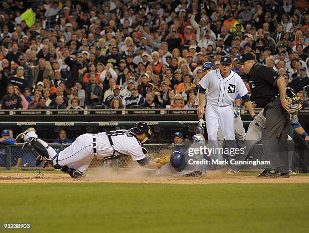 Yuniesky Betancourt of the Kansas City Royals slides into home while Gerald Laird of the Detroit Tigers makes the tag as Eddie Bonine and homeplate...