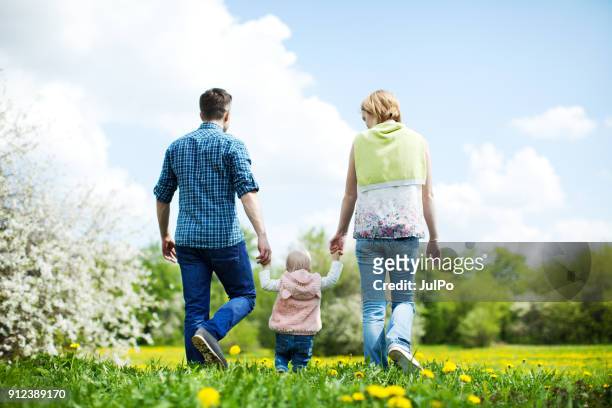 glückliche familie im freien - hand in hand spazieren stock-fotos und bilder