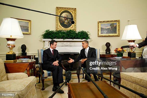 President Barack Obama extends his hand for a handshake with NATO Secretary General Anders Fogh Rasmussen in the Oval Office at the White House...