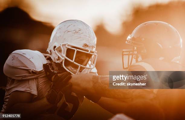 aggressive american football players on a field at sunset. - wide receiver athlete stock pictures, royalty-free photos & images