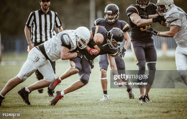 determined american football players tackling during the game on playing field. - american football tackle stock pictures, royalty-free photos & images
