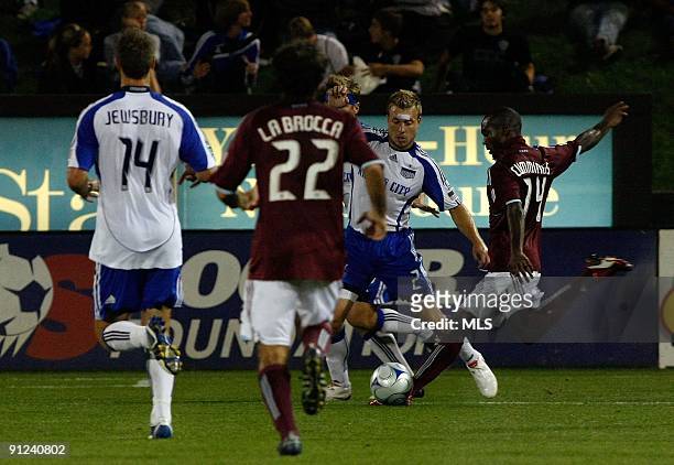 Forward Omar Cummings of the Colorado Rapids tries to get a shot on goal past defender Michael Harrington of the Kansas City Wizards while defender...