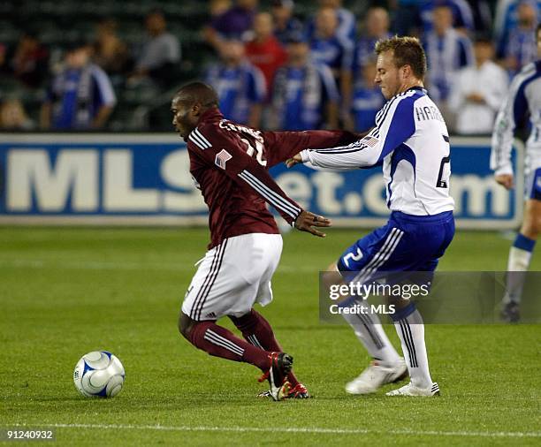 Forward Omar Cummings of the Colorado Rapids tries to fend off defender Michael Harrington of the Kansas City Wizards during the second half of their...