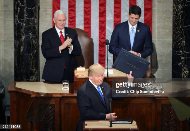 President Donald J. Trump holds up his speech as U.S. Vice President Mike Pence and Speaker of the House U.S. Rep. Paul Ryan look on during the State...