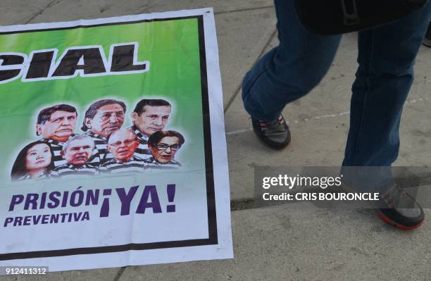 Demonstrator walks past a banner calling for preventive detention of Peruvian former presidents Alan Garcia, Alejandro Toledo and Ollanta Humala...