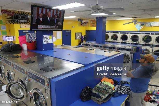 Lenin Rosales does his laundry at the Coral Way Lavanderia coin laundry as he watches a television broadcast of U.S. President Donald Trump as he...