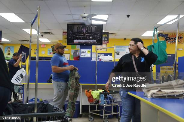 Lenin Rosales and Ilda Moreno fold their laundry at the Coral Way Lavanderia coin laundry as a television broadcast of U.S. President Donald Trump is...