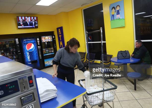 Talia Ayala folds her laundry at the Coral Way Lavanderia coin laundry as a television broadcast of U.S. President Donald Trump is seen as he...