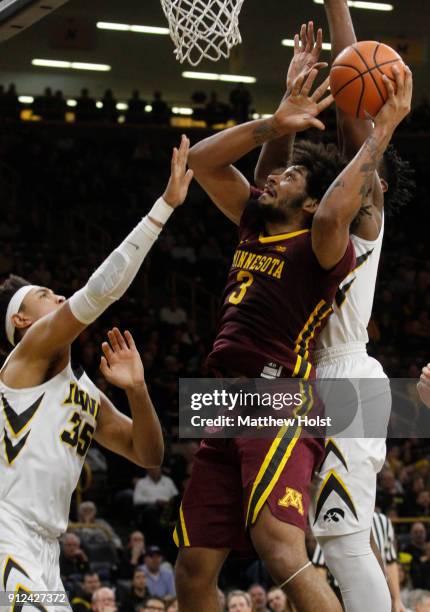 Forward Jordan Murphy of the Minnesota Gophers goes to the basket in the first half between forwards Cordell Pemsl and Tyler Cook of the Iowa...