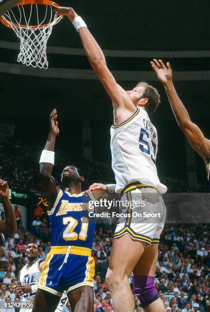 Mark Eaton of the Utah Jazz tips it in over Michael Cooper of the Los Angeles Lakers during an NBA basketball game circa 1989 at the Salt Palace in...