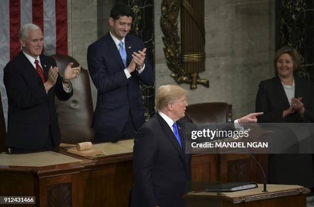 President Donald Trump points at members of the audience as US Vice President Mike Pence and Speaker of the House Paul Ryan clap following Trump's...