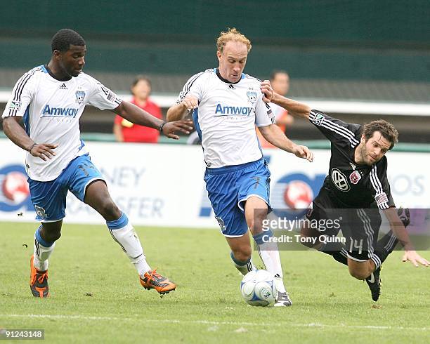 Ben Olsen of D.C. United is knocked off the ball by Simon Elliott and Brandon McDonald of the San Jose Earthquakes during an MLS match at RFK Stadium...