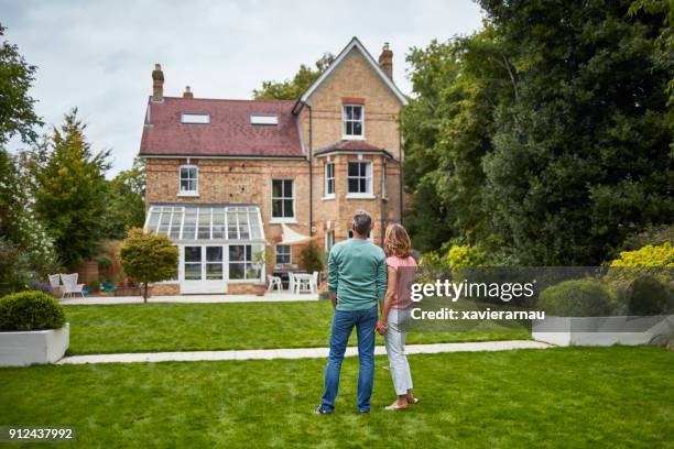 achteraanzicht van de paar op gras kijken naar huis - person standing infront of wall stockfoto's en -beelden