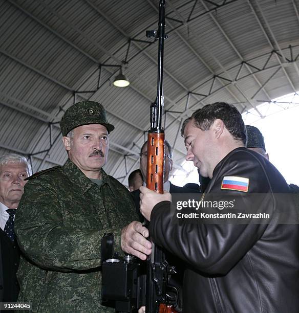 Russian President Dmitry Medvedev and Belarusian President Alexander Lukashenko examine a sniper rifle while visiting a military base during combined...