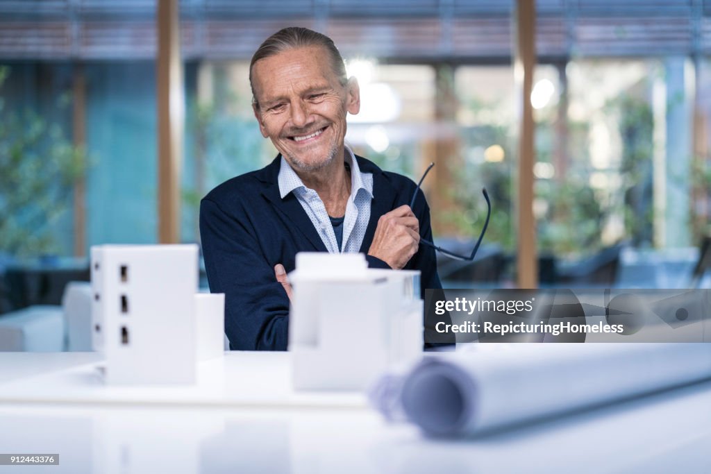 Architect looking at his architectural model while smiling