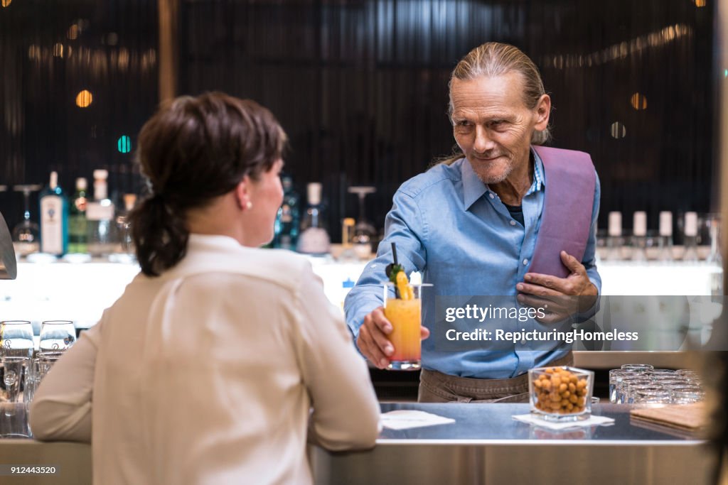 Barman sirviendo una bebida a un cliente femenino
