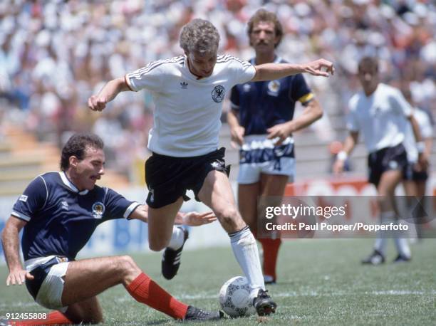 West German striker Rudi Voller is tackled by Scotland defender Willie Miller during the FIFA World Cup match between Scotland and West Germany at...