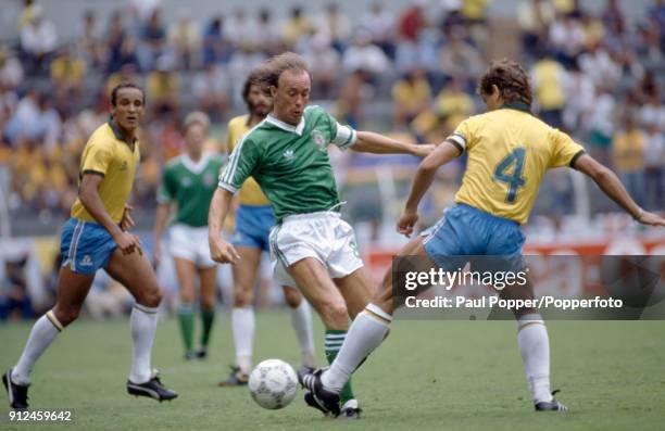 Sammy McIlroy of Northern Ireland is tackled by Edinho of Brazil, watched by Elzo during the FIFA World Cup match between Northern Ireland and Brazil...