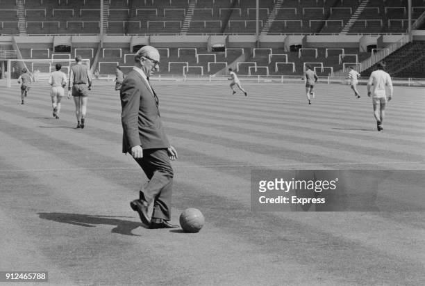 Manchester United FC manager Matt Busby about to kick a soccer ball during training ahead of the European Cup Final at Wembley Stadium, London, UK,...